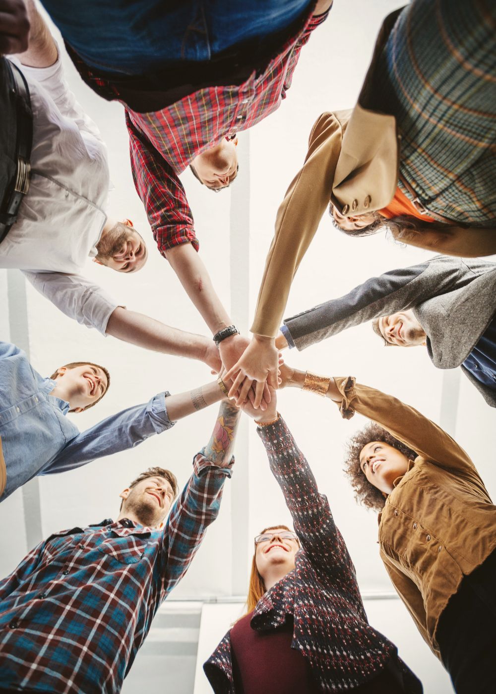 Zusammenarbeit auf Augenhöhe – selbstorganisierte Teams stärken Ein Team steht im Kreis und streckt die Hände gemeinsam nach innen – Sinnbild für Zusammenhalt, Eigenverantwortung und kooperative Zusammenarbeit in selbstorganisierten Teams.